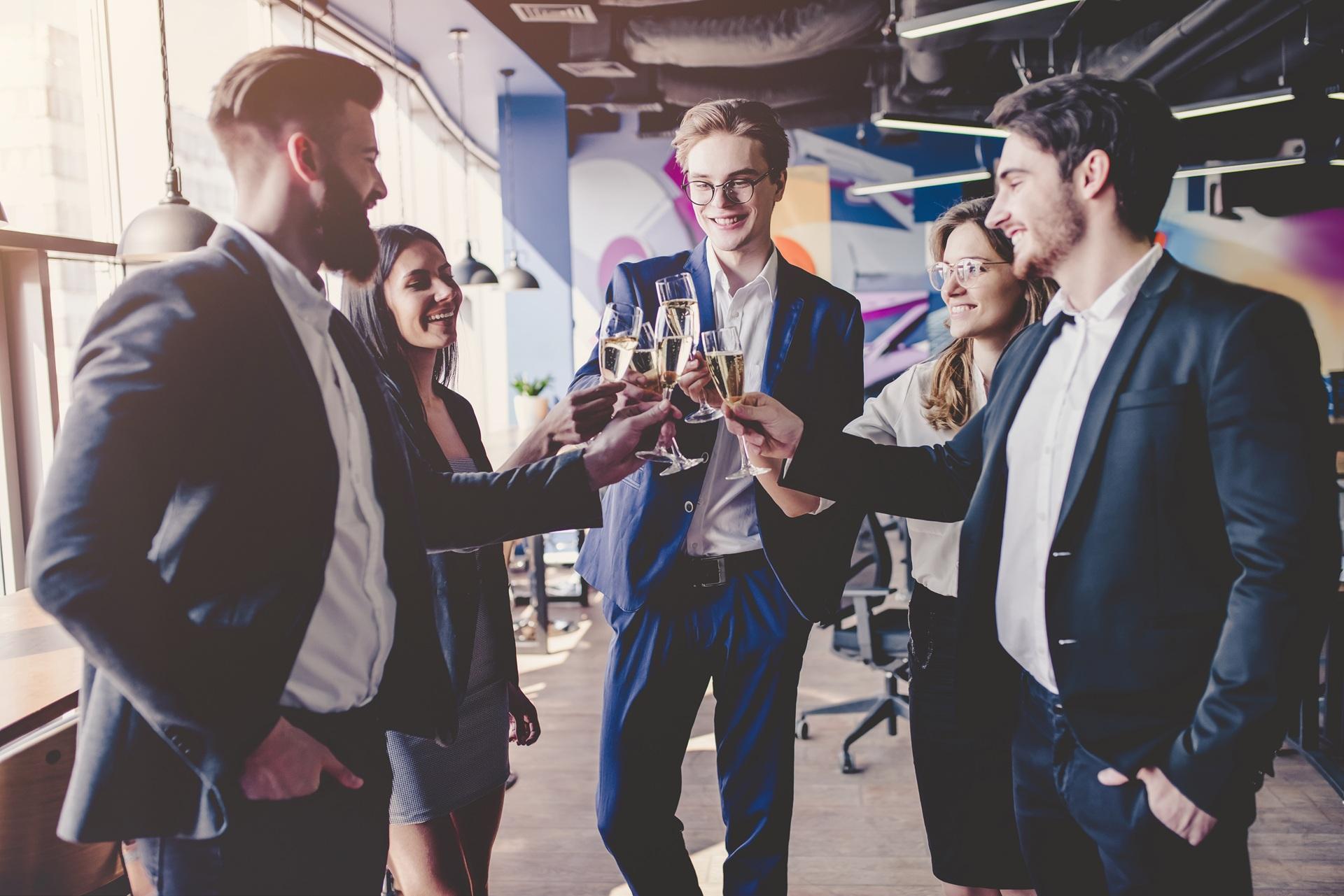 Fünf junge Menschen stoßen im modernen Büro an | Eventzelte